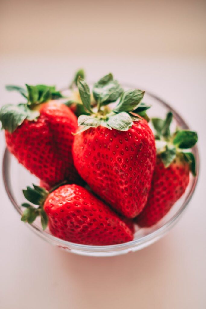 Services A close-up of bright red strawberries in a clear glass bowl on a soft background.