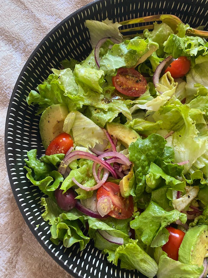 brand-01 Bright and healthy salad featuring lettuce, avocado, cherry tomatoes, and onions.